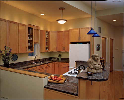 
Though modest in size, the kitchen provides creative cooking space under the auspices of the Laughing Buddha, who invites prosperity and abundance into the household. Because the kitchen conveniently opens onto the dining area, the FSC-certified maple cabinets, arched faucet, and elegant granite can be enjoyed from other parts of the house. “I chose this gorgeous granite because it reminds me of swirls of sea foam left on the sand when the tide goes out,” Ray says.
